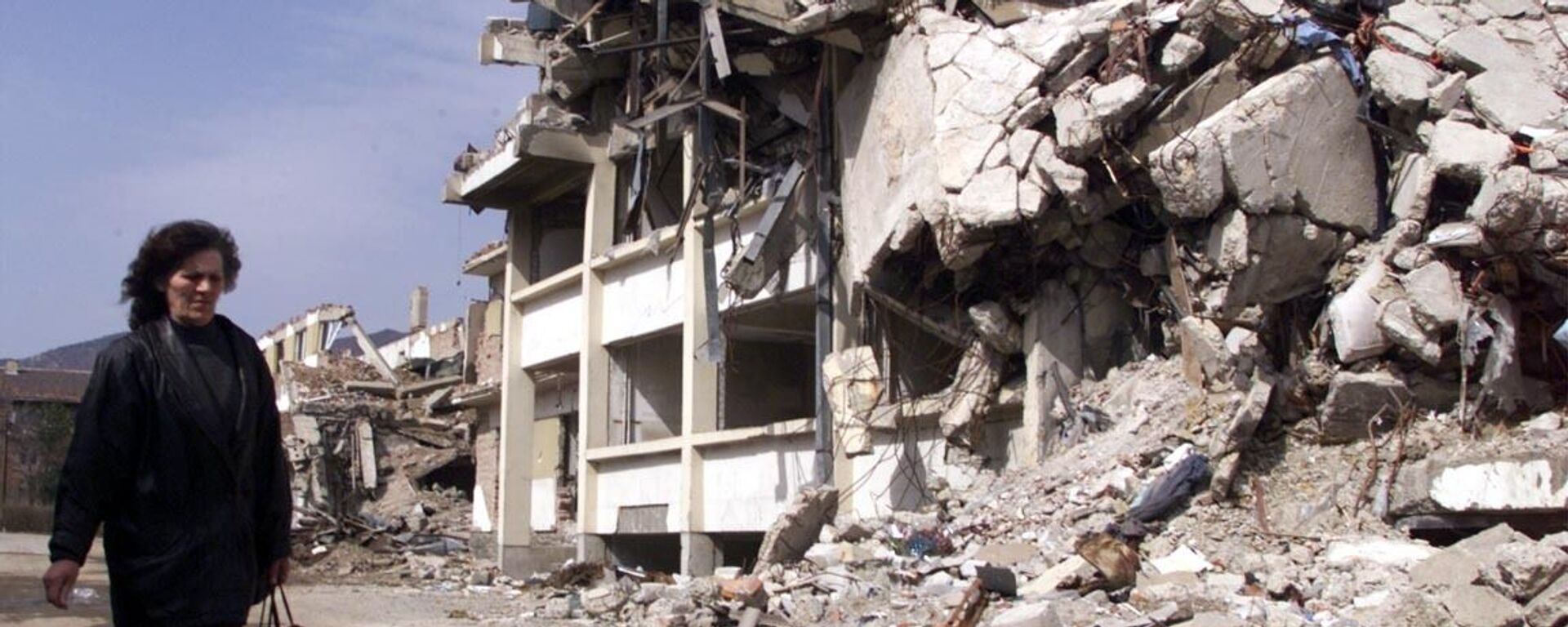 Người phụ nữ đi ngang qua tòa nhà ở Kosovska Mitrovica (Nam Tư) bị phá hủy bởi bom NATO, năm 1999 - Sputnik Việt Nam, 1920, 26.01.2022