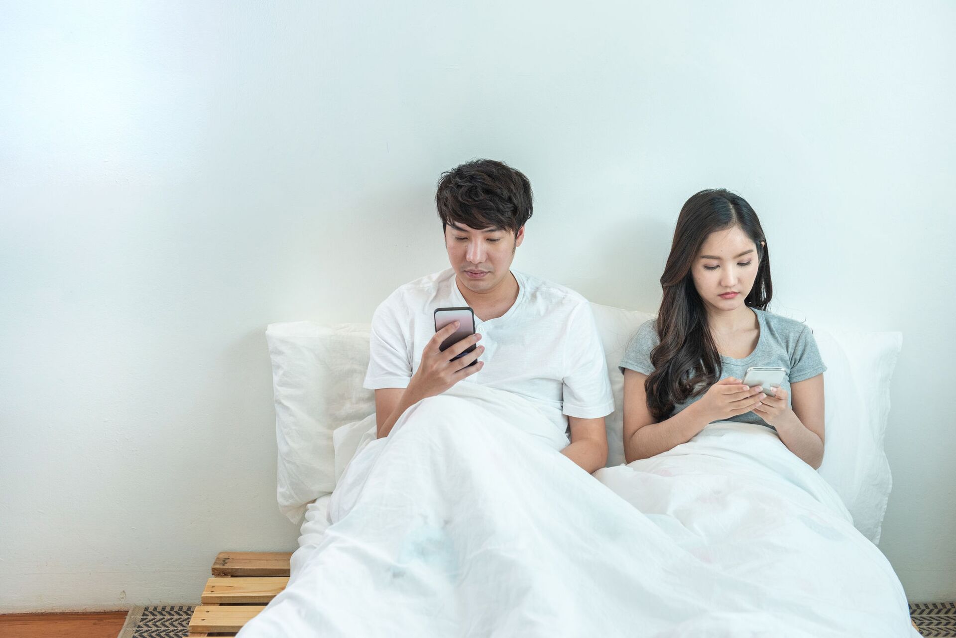 Cặp vợ chồng trẻ trên giường đang xem điện thoại - Sputnik Việt Nam, 1920, 27.01.2022