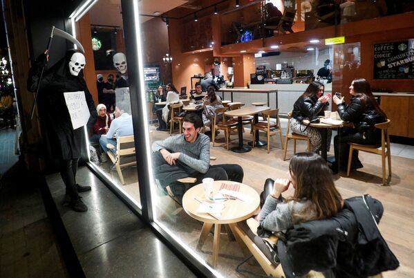 Mọi người trong quán cà phê cười một người biểu tình chống lại các hạn chế COVID-19 mặc trang phục &#x27;tử thần&#x27; ở Barcelona - Sputnik Việt Nam