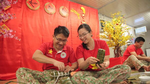 Сác cán bộ, nhân viên Bệnh viện dã chiến cấp 2 số 3 (BVDC 2.3) vẫn cố gắng mỗi người một việc, quây quần bên nhau cùng gói những chiếc bánh chưng - Sputnik Việt Nam