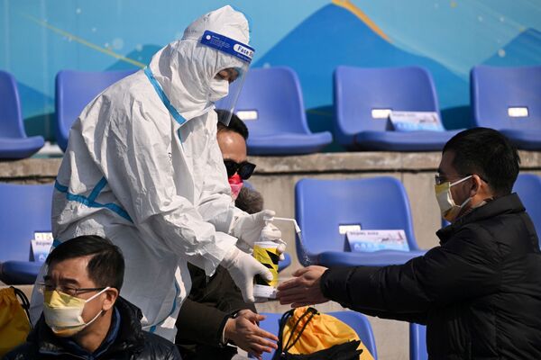 Một nhân viên mặc thiết bị bảo hộ cá nhân xịt chất khử trùng lên tay khán giả ở Bắc Kinh - Sputnik Việt Nam