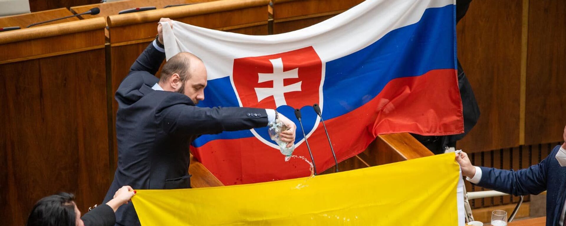 Andriy Medvecki, thành viên của Đảng Nhân dân cực hữu Slovakia của chúng ta, đã đổ nước lên lá cờ của Ukraine tại Quốc hội Slovakia - Sputnik Việt Nam, 1920, 11.02.2022