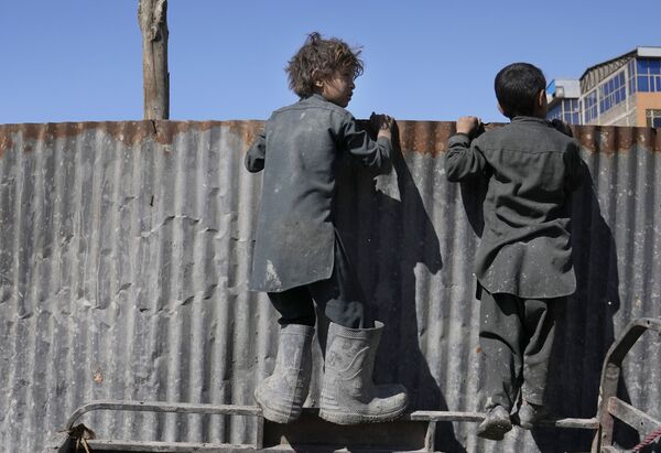 Các cậu bé Afghanistan nhìn qua hàng rào khi viện trợ nhân đạo được phân phát cho các gia đình khó khăn ở Kabul - Sputnik Việt Nam