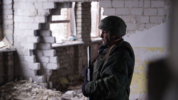 Một binh sĩ của LNR kiểm tra một ngôi trường bị phá hủy ở làng Molodyozhny, vùng Luhansk - Sputnik Việt Nam