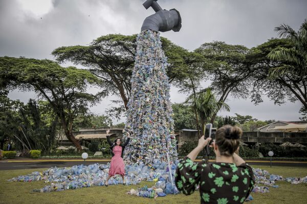 Du khách tạo dáng chụp ảnh trước chiếc vòi khổng lồ rót ra dòng chai nhựa ở Nairobi, Kenya - Sputnik Việt Nam