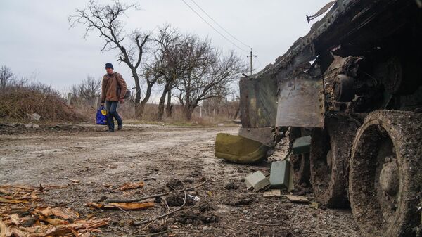 Một cư dân làng Gnutovo đi ngang qua chiếc xe tăng của quân đội Ukraina bị bắn cháy gần Mariupol - Sputnik Việt Nam
