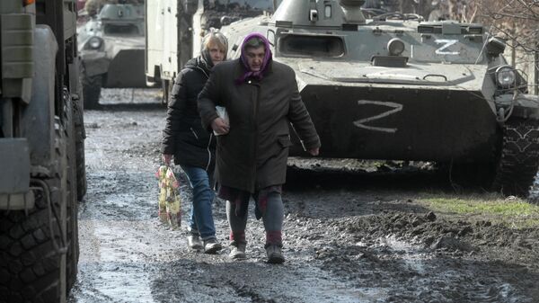 Người dân đi ngang qua một cột khí tài quân sự ở làng Svobodnoye, Cộng hòa Nhân dân Donetsk. - Sputnik Việt Nam