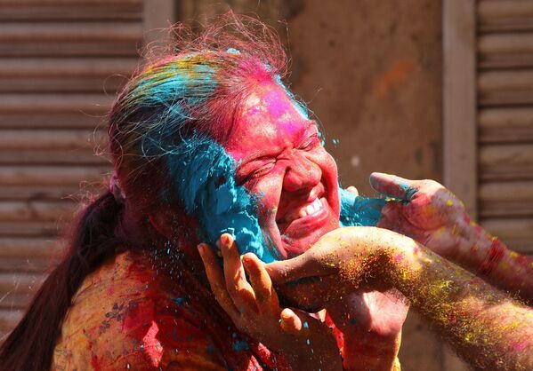 Người phụ nữ cười khi bôi bột màu lên mặt trong lễ kỷ niệm Holi ở Kolkata - Sputnik Việt Nam