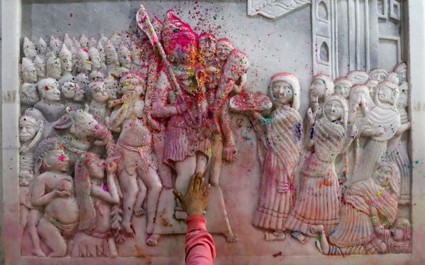 Người đàn ông bôi bột màu lên các bức tranh tường tôn giáo bên trong ngôi đền trong lễ kỷ niệm Holi ở các khu phố cổ Delhi - Sputnik Việt Nam
