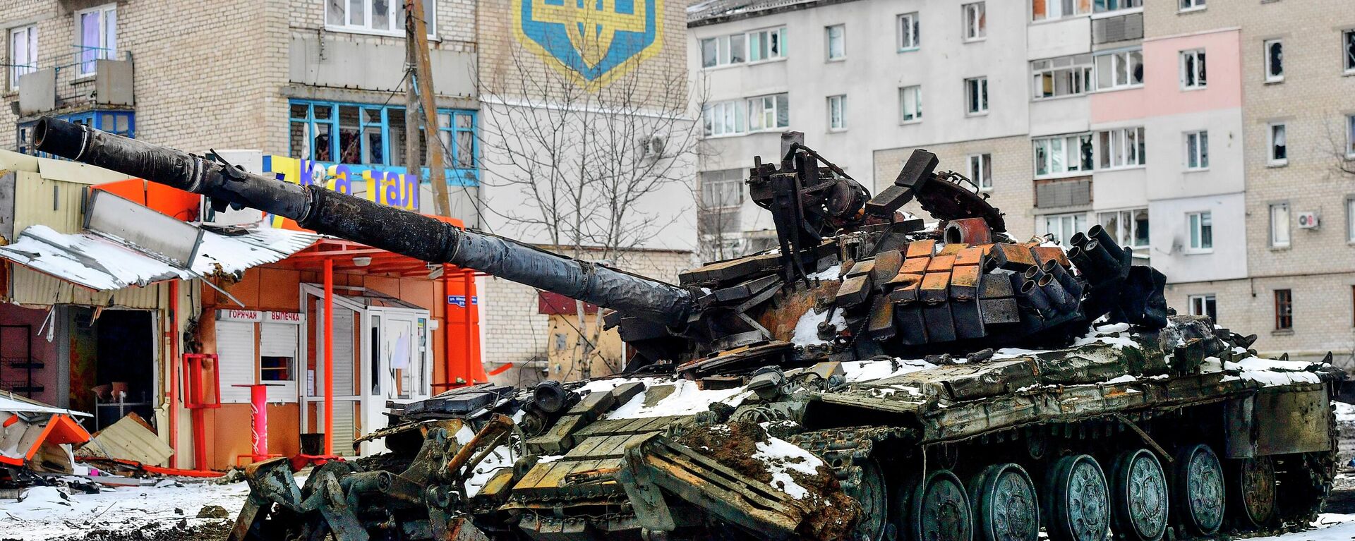 Xe tăng bị phá hủy của Lực lượng vũ trang Ukraine gần ngôi nhà có quốc huy Ukraine ở Volnovakha - Sputnik Việt Nam, 1920, 04.04.2022