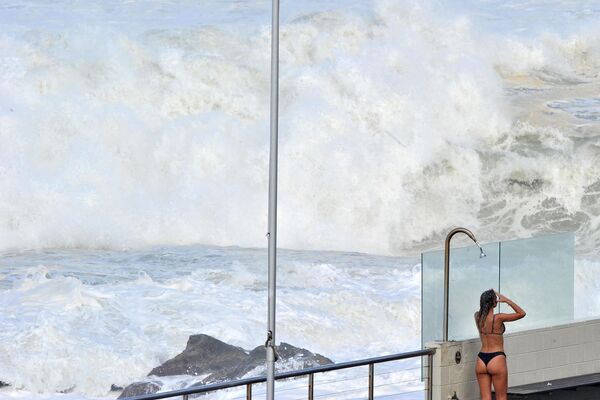 Cô gái tắm sau khi bơi trên nền những con sóng khổng lồ tại bãi biển Bondi ở Sydney - Sputnik Việt Nam