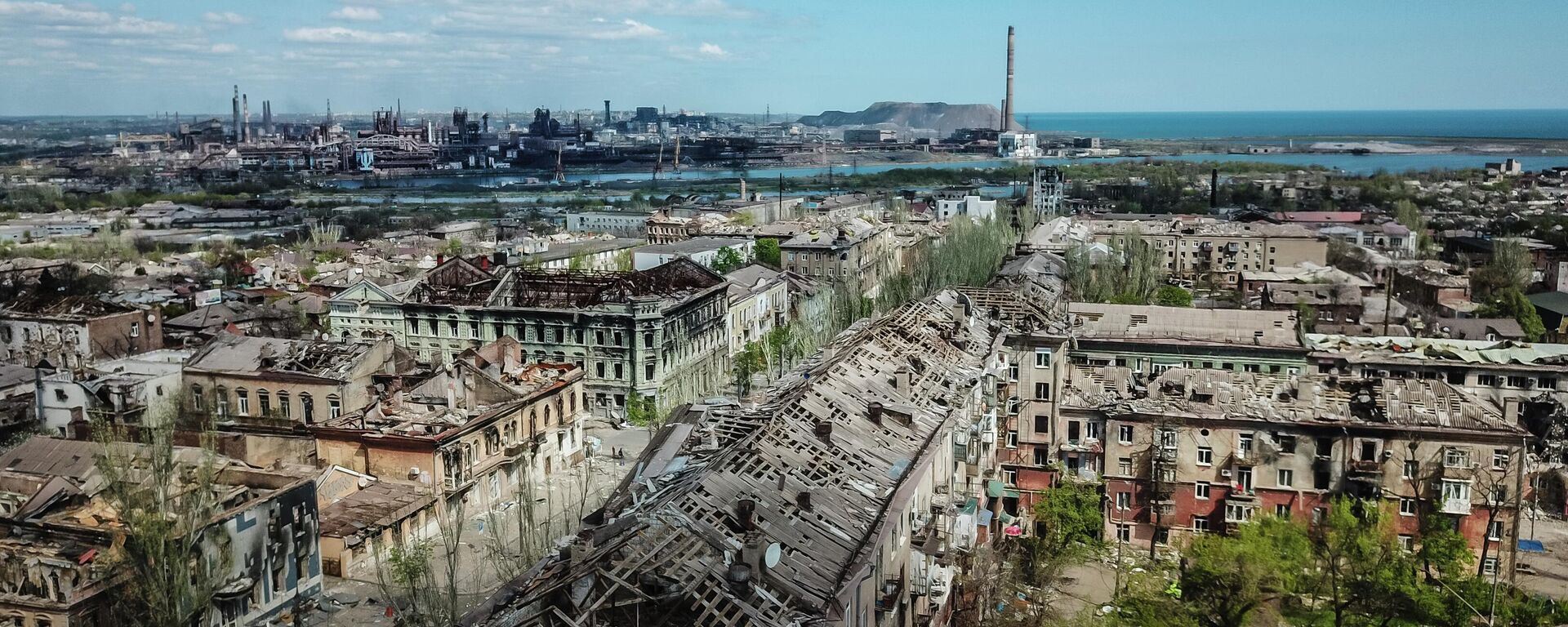 Các tòa nhà bị phá hủy ở trung tâm Mariupol. Ở hậu cảnh là nhà máy luyện kim Azovstal. - Sputnik Việt Nam, 1920, 01.05.2022