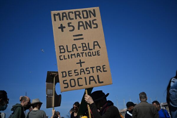 Một người diễn hành cầm biểu ngữ ghi &quot;Macron + 5 năm = khí hậu blah blah + thảm họa xã hội&quot; trong Ngày Một tháng Năm hàng năm (Ngày Lao động) kỷ niệm ngày quốc tế công nhân ở Marseille, miền nam nước Pháp, ngày 1 tháng 5 năm 2022. - Sputnik Việt Nam
