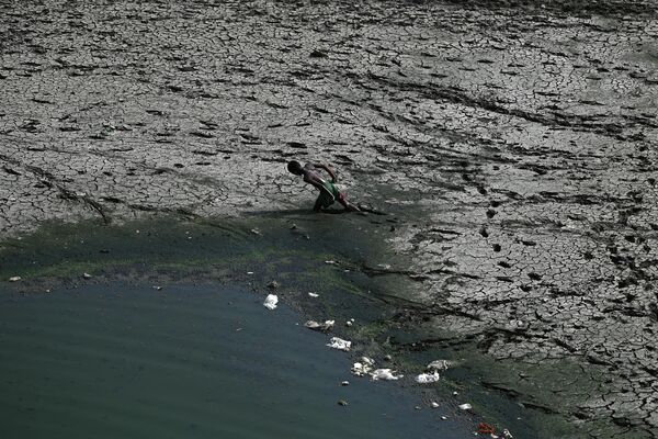 Cậu bé đi dọc theo dòng cạn khô của sông Yamuna trong ngày nắng nóng ở New Delhi, Ấn Độ - Sputnik Việt Nam