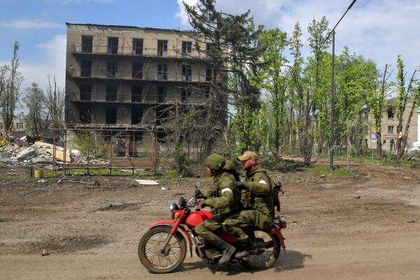 Những người lính đi xe máy qua những ngôi nhà bị phá hủy ở thị trấn Popasna  - Sputnik Việt Nam