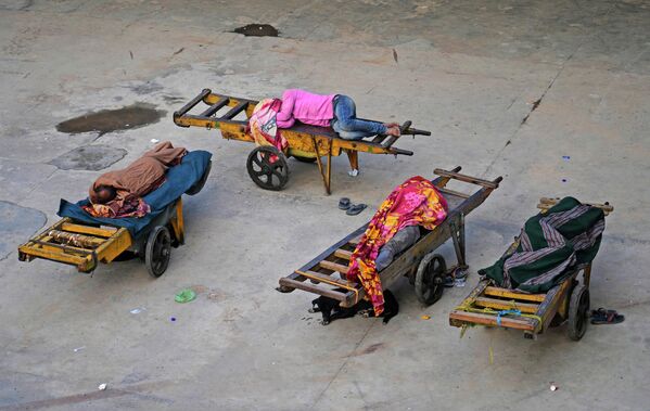Những người khuân vác ngủ trên xe đẩy tay của họ tại nhà ga xe lửa ở New Delhi, Ấn Độ. - Sputnik Việt Nam