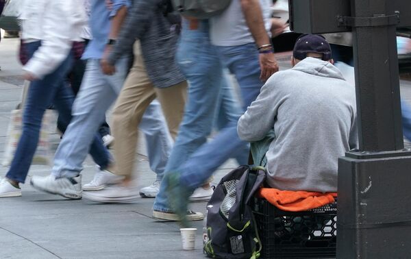 Những người đi bộ trên Đại lộ số 5 đi ngang qua một người đàn ông đang xin tiền ở New York. - Sputnik Việt Nam