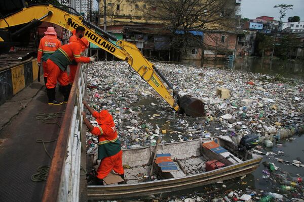 Công nhân thành phố dọn dẹp các mảnh vỡ trôi trên sông Negro, nước dâng do mưa, ở Manaus, Brazil. - Sputnik Việt Nam