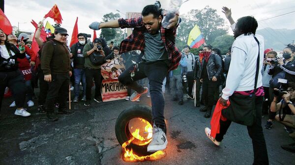 Một học sinh nhảy qua chiếc lốp xe đang cháy trong cuộc biểu tình chống chính phủ ở Quito - Sputnik Việt Nam
