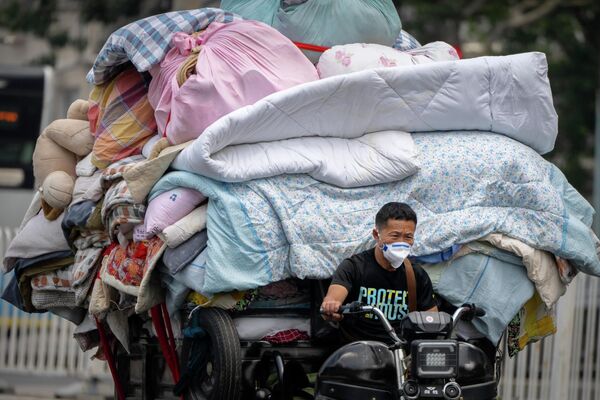 Một người điều khiển mô tô đẩy một xe hàng chất đầy giường trên phố ở Bắc Kinh. - Sputnik Việt Nam