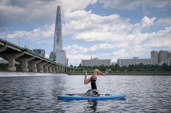 Tập yoga trên ván chèo trước tháp Lotte trên sông Hàn ở Seoul. - Sputnik Việt Nam