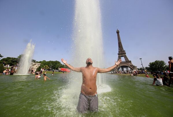 Một người đàn ông tắm mát trong đài phun nước Trocadero trước Tháp Eiffel ở Paris. - Sputnik Việt Nam