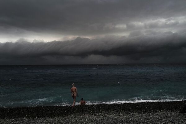 Hai người đi nghỉ mát nhìn những đám mây trước cơn bão trên Promenade des Anglais ở Nice - Sputnik Việt Nam
