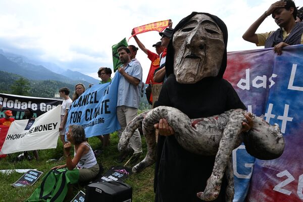 Người biểu tình cầm biểu ngữ, logo, búp bê và mặt nạ trong cuộc biểu tình phản đối hội nghị thượng đỉnh G7 - Sputnik Việt Nam