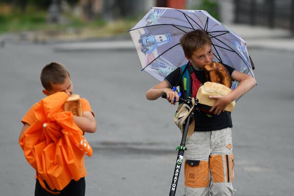 Trẻ em ăn bánh mì gần một trạm cứu trợ di động gần Nhà thờ Pokrovski ở Mariupol - Sputnik Việt Nam