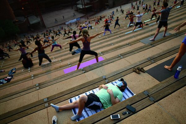 Người đàn ông ngủ trong khi những người khác tập yoga buổi sáng tại Nhà hát vòng tròn Red Rocks ở Morrison, Colorado - Sputnik Việt Nam