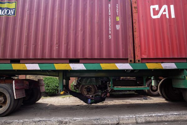 Tài xế xe tải ngủ dưới gầm xe đậu bên đường khi chờ vào cảng Tincan ở Apapa, Lagos - Sputnik Việt Nam