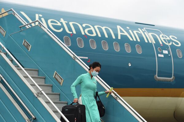 Một thành viên tổ bay của      Vietnam Airlines đeo khẩu trang phòng coronavirus COVID-19 đang rời khỏi      chuyến bay trở về từ Đài Loan tại sân bay quốc tế Nội Bài, Hà Nội ngày 3 tháng 3 năm 2020. - Sputnik Việt Nam