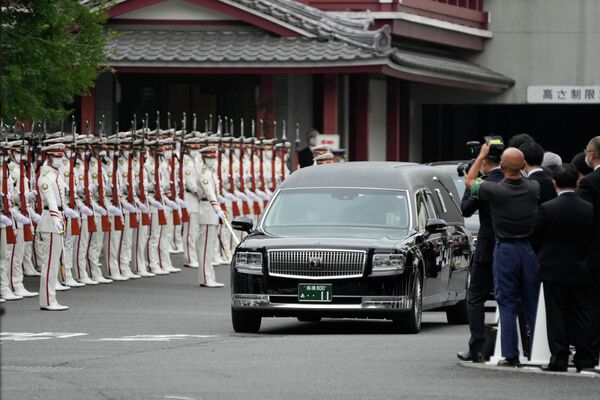 Chiếc xe tang chở thi hài của cựu Thủ tướng Nhật Bản Shinzo Abe di chuyển giữa đội bảo vệ danh dự và những người tham dự khi ông rời chùa Jojoji sau lễ tang của ông ở Tokyo vào thứ Ba, ngày 12 tháng 7 năm 2022. - Sputnik Việt Nam