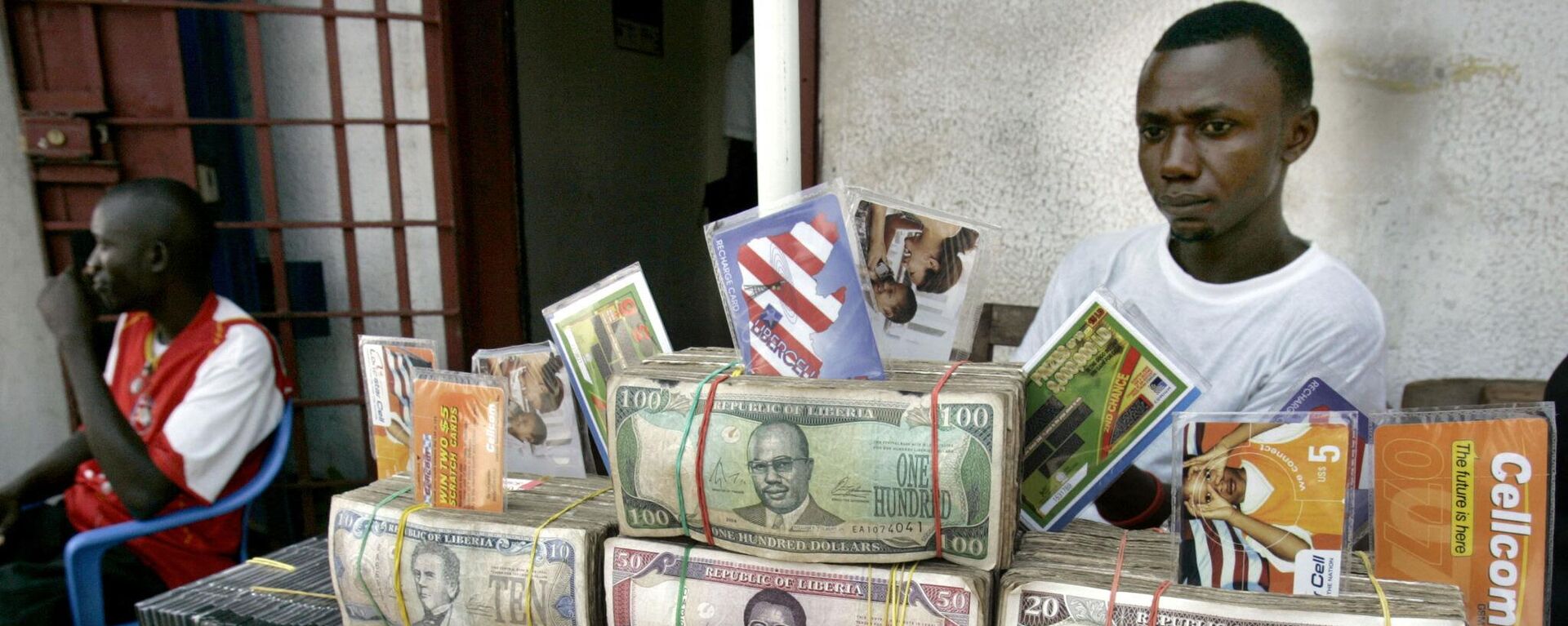 Những tệp đô la Liberia trên bàn tại văn phòng thu đổi ngoại tệ ở thủ đô Liberia - Sputnik Việt Nam, 1920, 19.07.2022