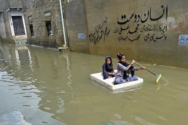Những bé gái trên con bè vượt qua phố ngập lụt sau trận mưa lớn trong khu dân cư ở Karachi, Pakistan. - Sputnik Việt Nam
