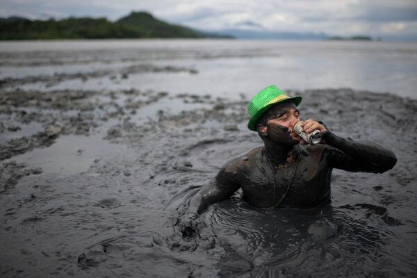 Người đàn ông uống bia khi tham gia lễ hội bùn &quot;Block da Lama&quot; ở Paraty, bang Rio de Janeiro, Brazil - Sputnik Việt Nam