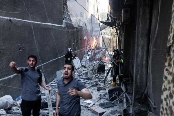 Lực lượng cứu hộ và lính cứu hỏa dập lửa trong bối cảnh bị tàn phá sau cuộc không kích của Israel vào thành phố Gaza. - Sputnik Việt Nam