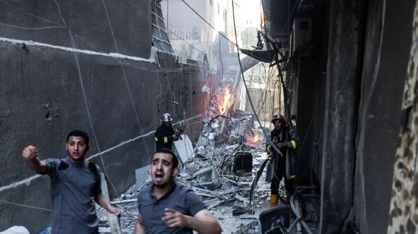 Lực lượng cứu hộ và lính cứu hỏa dập lửa trong bối cảnh bị tàn phá sau cuộc không kích của Israel vào thành phố Gaza - Sputnik Việt Nam