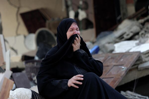 Người phụ nữ khóc bên ngoài ngôi nhà bị phá hủy sau khi Israel tấn công Dải Gaza. - Sputnik Việt Nam