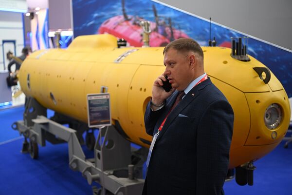 Vị khách tham quan nói chuyện điện thoại bên cạnh mô hình tàu ngầm trưng bày trong khuôn khổ Diễn đàn Kỹ thuật-Quân sự Quốc tế «Army-2022» tại Trung tâm Triển lãm-Hội nghị «Patriot». - Sputnik Việt Nam