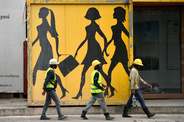 Công nhân xây dựng đi qua một bức tranh tường ở Phnom Penh. - Sputnik Việt Nam