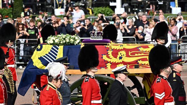 Quan tài  Nữ hoàng Elizabeth II, được trang trí bằng Tiêu chuẩn Hoàng gia và Vương miện Hoàng gia, được nhìn thấy trong đám rước từ Cung điện Buckingham đến Cung điện Westminster ở London. - Sputnik Việt Nam