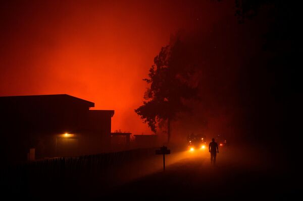 Lính cứu hỏa đi ngang qua những ngôi nhà đang bị cháy rừng đe dọa ở Somoza, Pháp. - Sputnik Việt Nam