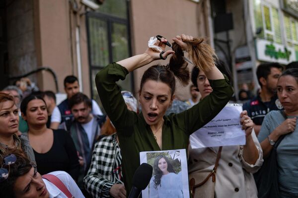 Cô gái Iran Nasibe Samael hiện sống ở Thổ Nhĩ Kỳ cắt tóc mình trong cuộc biểu tình trước Toà Lãnh sự quán Iran ở Istanbul. - Sputnik Việt Nam