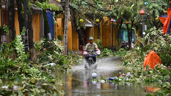 Người đàn ông đi xe trên đường phố ngập lụt sau khi cơn bão Noru đi qua tại thành phố Hội An, tỉnh Quảng Nam, Việt Nam - Sputnik Việt Nam