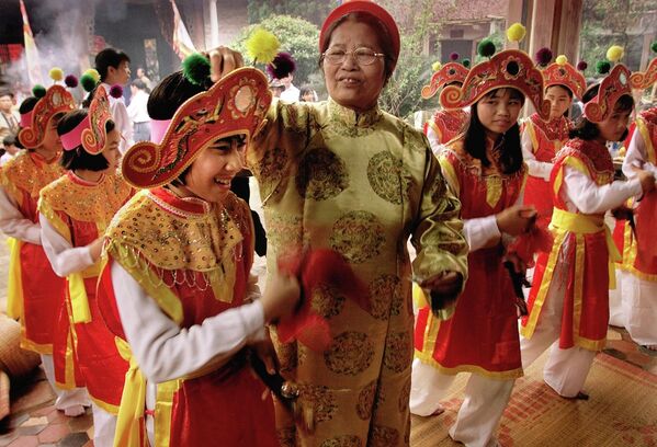 Người phụ nữ đặt tiền vàng mã như lễ vật vào mũ của vũ nữ trẻ tuổi tại một ngôi chùa khi bắt đầu lễ hội mùa xuân kéo dài 3 ngày ở làng Chử Đồng Tử, miền Bắc Việt Nam - Sputnik Việt Nam