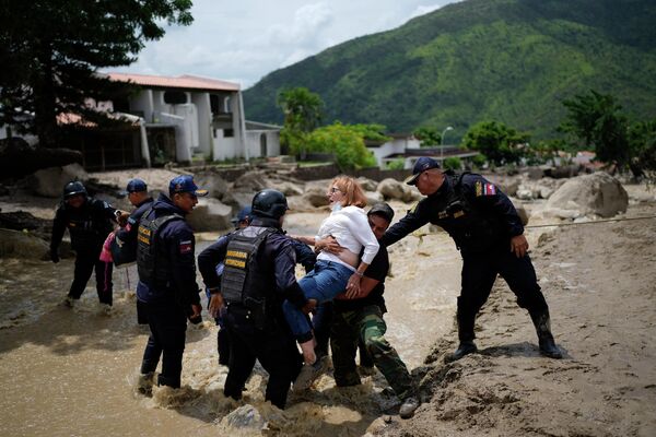 Cảnh sát đưa người phụ nữ qua con phố ngập lụt ở El Castano, Venezuela. - Sputnik Việt Nam