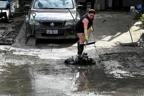 Một người phụ nữ quét bùn đất trên khu vực bị ảnh hưởng bởi lũ lụt ở Maribyrnong, ngoại ô Melbourne, Australia. - Sputnik Việt Nam
