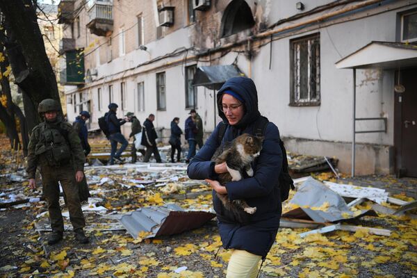 Cô gái với con mèo gần một tòa nhà dân cư bị hư hại do pháo kích ở Donetsk. - Sputnik Việt Nam