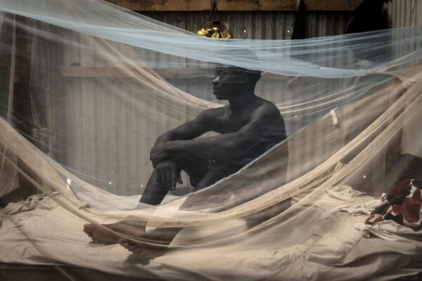 Người thợ xây dựng từ Sierra Leone ngồi trên giường của mình trong lán trại ở Diamniadio. - Sputnik Việt Nam